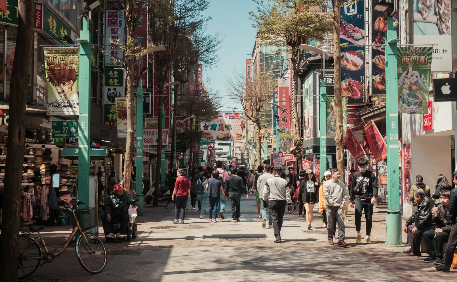 白天的台北西門町徒步街，行人往來、兩側商店招牌林立